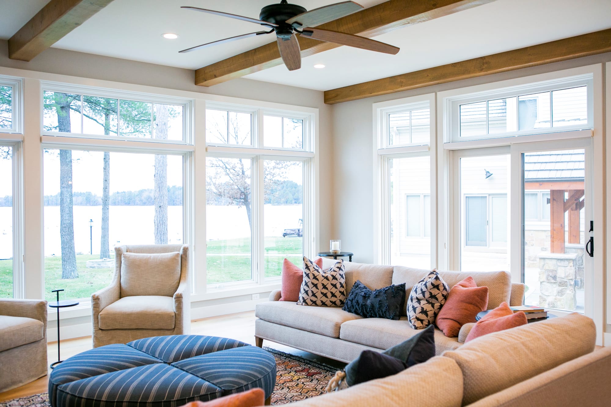 ake living with a stone floor to ceiling fireplace and cream colored upholstered furniture grouping with blue and terrra cotta accents.